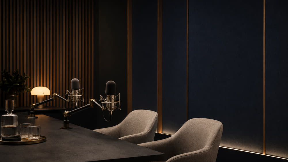 Two condenser microphones on booms above a felt-lined navy recording table in the Meridale audio studio.