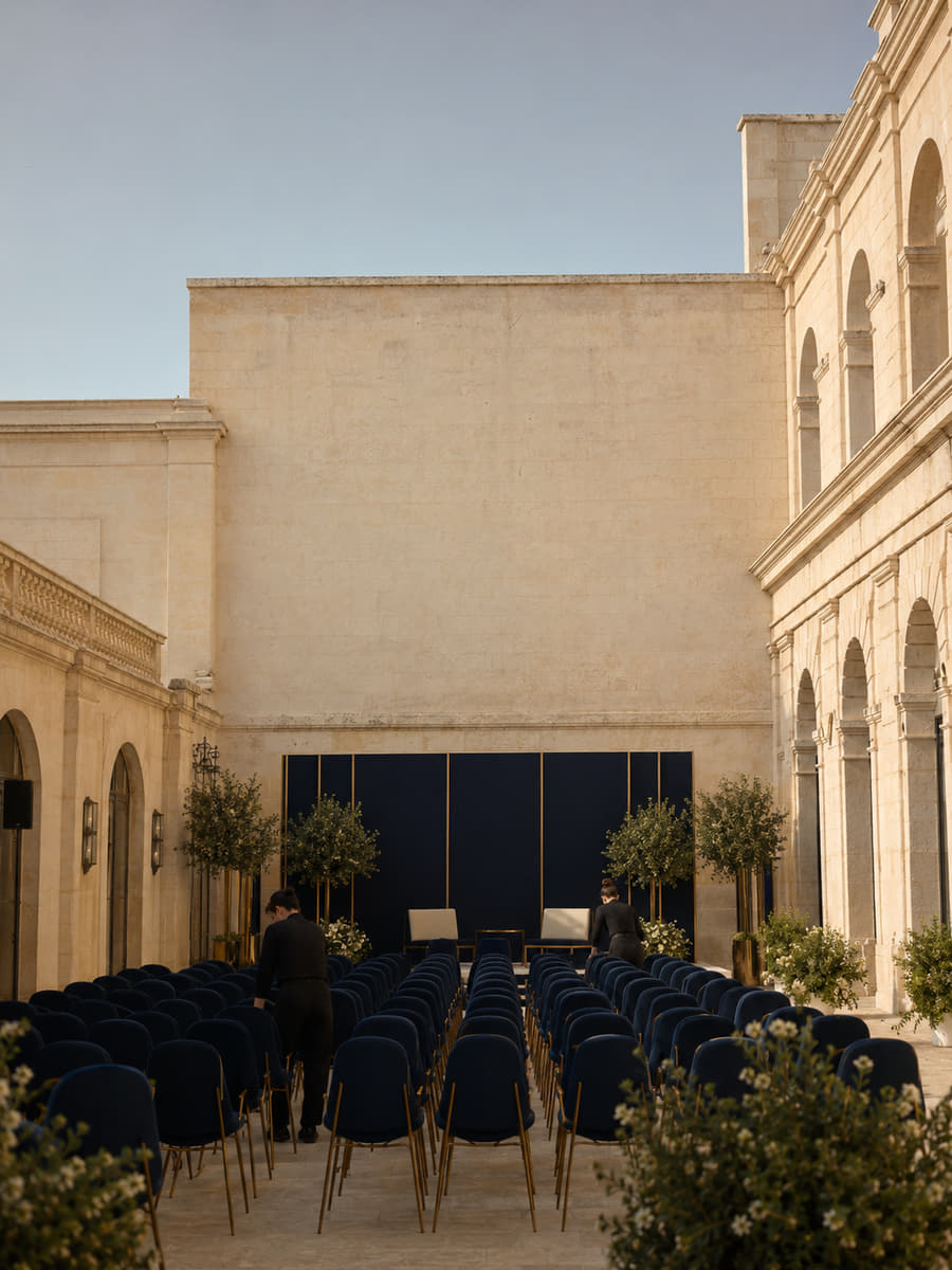 Rows of navy delegate chairs set out in a colonnaded stone courtyard before the opening session of a Montlior summit.