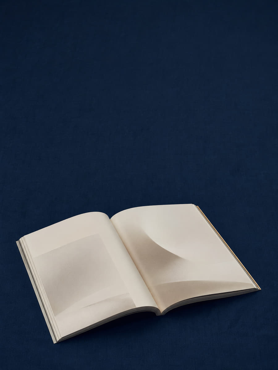An open book of blank cream pages lying on a deep navy surface.